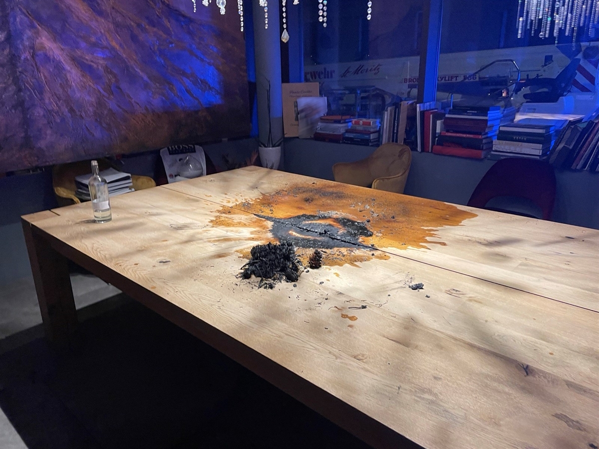 Die verbrannten Überreste des Adventskranzes auf einem Holztisch.