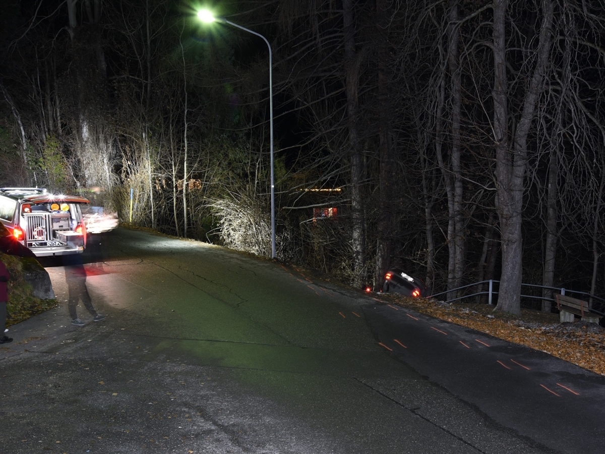 Am linken Strassenrand ein Polizeiauto. Rechts der Strasse Wald und das auf dem Dach liegende Auto.