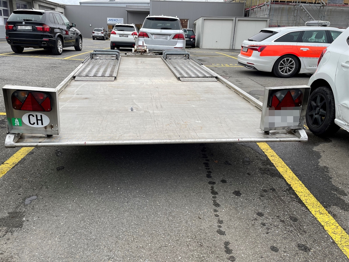 Der Anhänger. Im Hintergrund Autos, rechts ein Patrouillenwagen.