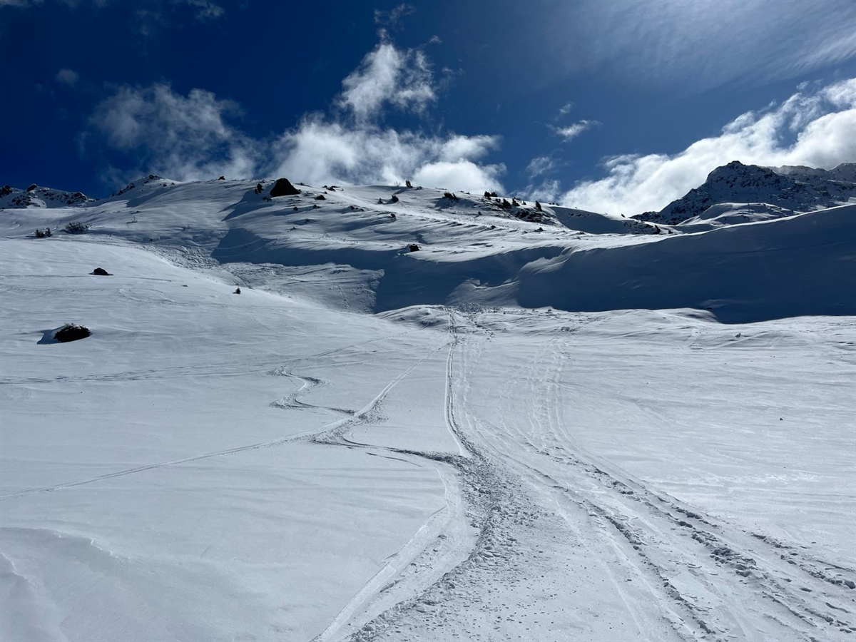 Übersichtsaufnahme im Bereich des Fundortes des Vermissten oberhalb von Parpan: Im Vordergrund frische Skispuren, im Hintergrund Fundort auf dem alten Lawinenkegel.