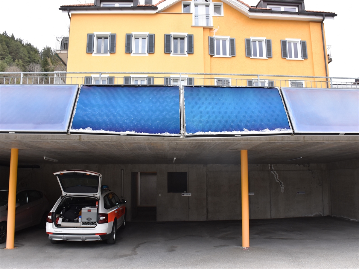 Blick auf einen Fahrzeugunterstand an welchem oben Solarpanels angebracht sind. Zwei davon sind beschädigt.