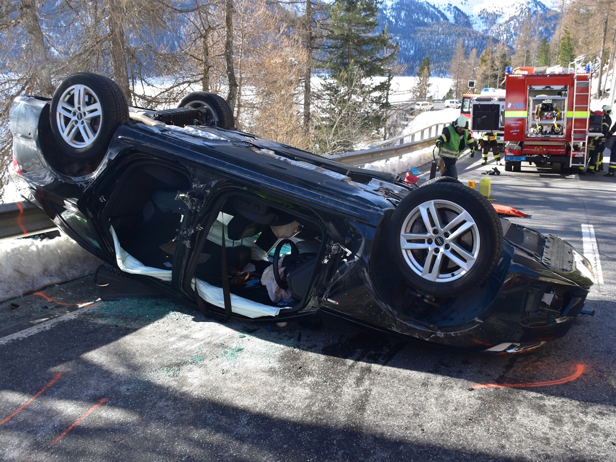 Im Vordergrund das Auto auf dem Dach. Im Hintergrund ein Einsatzfahrzeug und Einsatzkräfte sowie der Blick auf den gefrorenen Silvaplanersee.