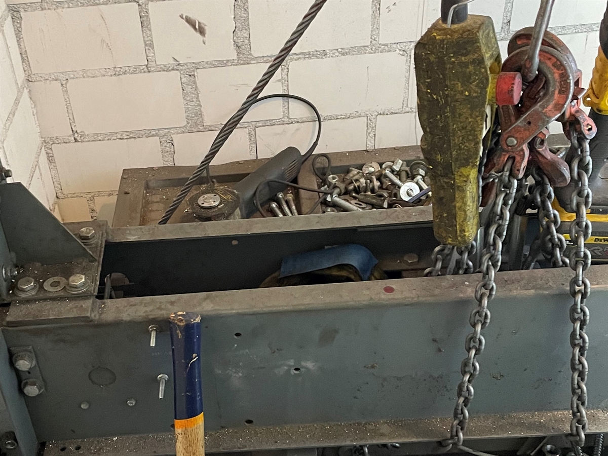 Auf einer an Seilen/Ketten hängenden Metallstruktur liegt eine Trennscheibe.