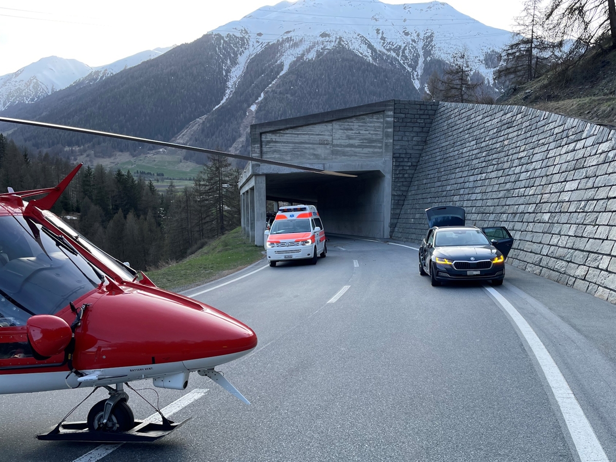 Das Unfallauto mit stark beschädigter rechter Seite. Vor der Galerie ein Rettungswagen. Im Vordergrund der Rega-Helikopter auf der Strasse.