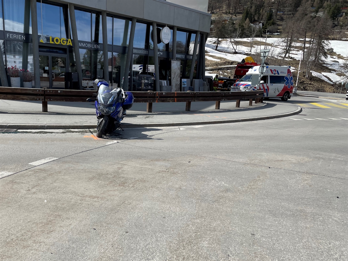 Das Motorrad steht auf dem Seitenständer abgestützt am Fahrbahnrand des Kreisels. Im Hintergrund aufgebotene Rettungswagen sowie das Abschleppfahrzeug.