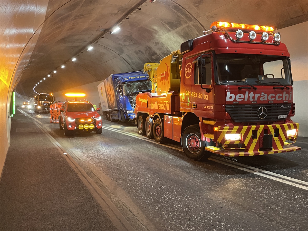 Ein Spezialfahrzeug einer Abschleppfirma birgt den Lastwagen. Ebenfalls im Tunnel steht hinter den Fahrzeugen die Putzmaschine des Tiefbauamtes Graubünden