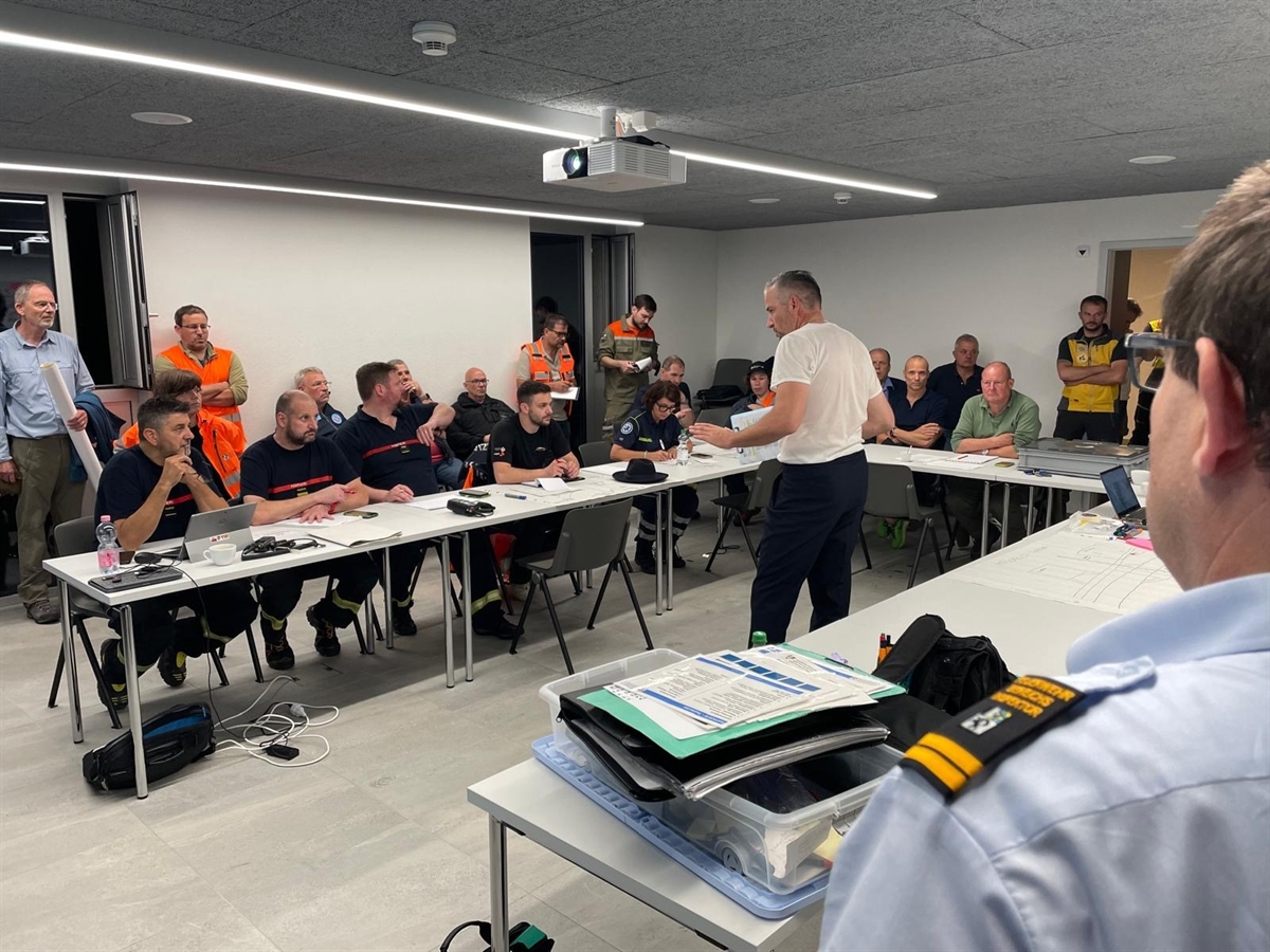 Einsatzkräfte bei einem von einem zivil gekleideten Polizisten geführten Lagerapport.