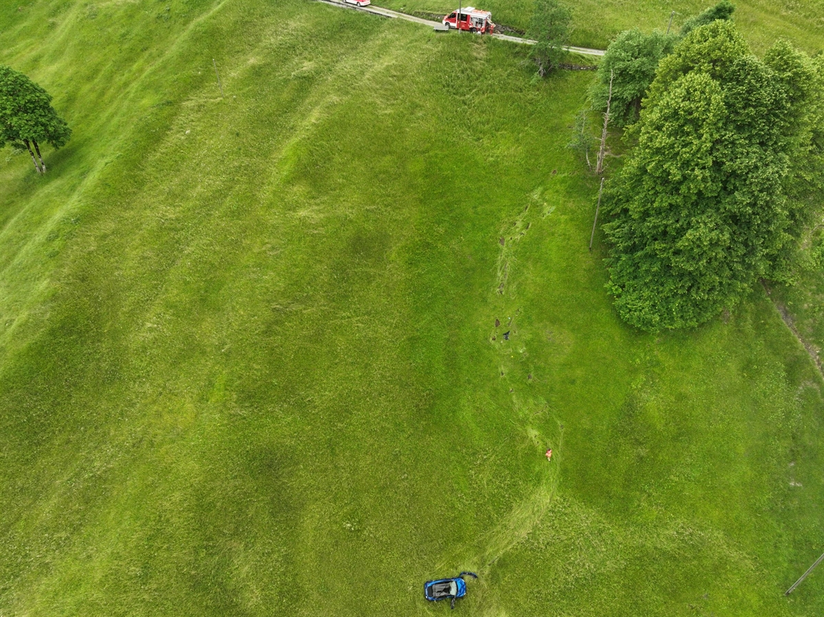 Steile Bergwiese unterhalb Strasse mit verunglücktem Fahrzeug
