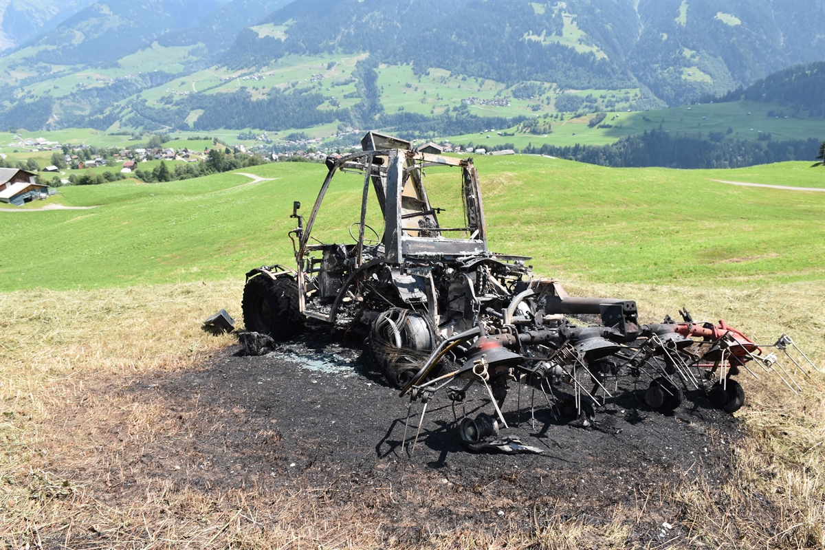 Ausgebrannter Traktor, im Hintergrund das Dorf