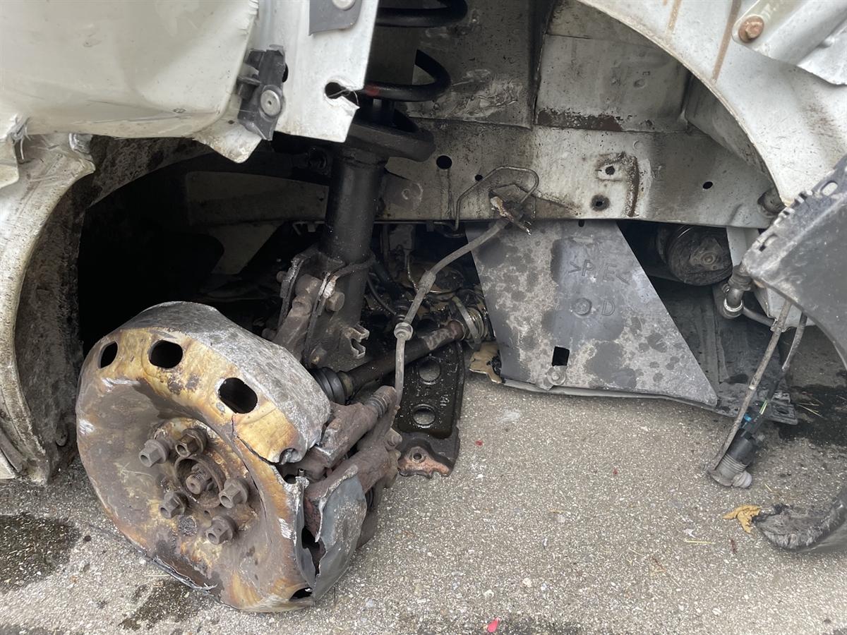 Die demolierte rechte vordere Radaufhängung des Lieferwagens mit der abgefahrenen Felge steht komplett auf der Fahrbahn auf.