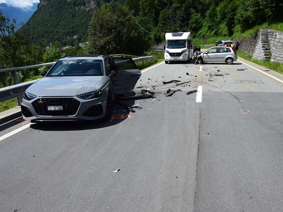 Links ein beschädigtes Auto. Im Hintergrund ein Wohnmotorwagen und ein weiteres Auto. Fahrzeugteile auf der Strasse. 