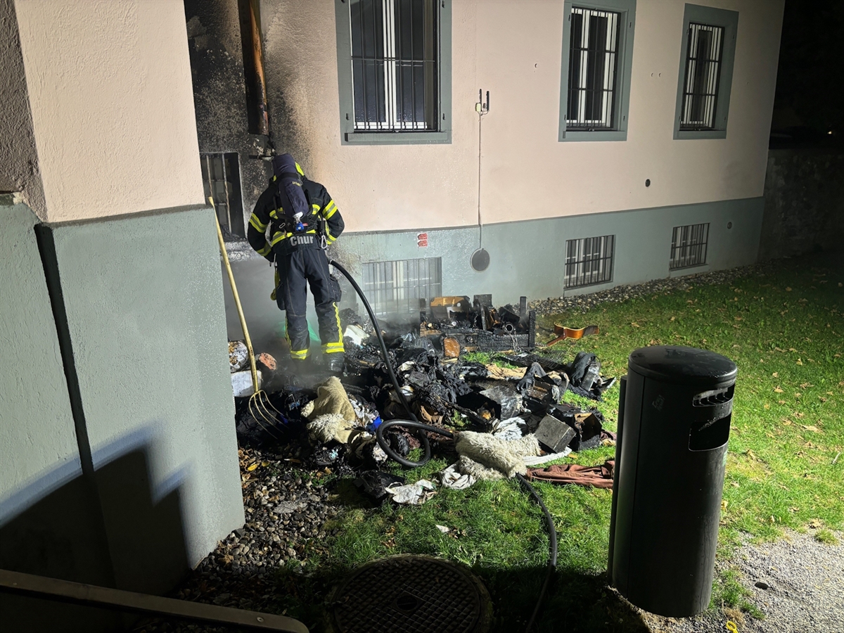 Ein Feuerwehrmann bei den Löscharbeiten des Hausrates. Im Hintergrund die beschädigte Fassade.