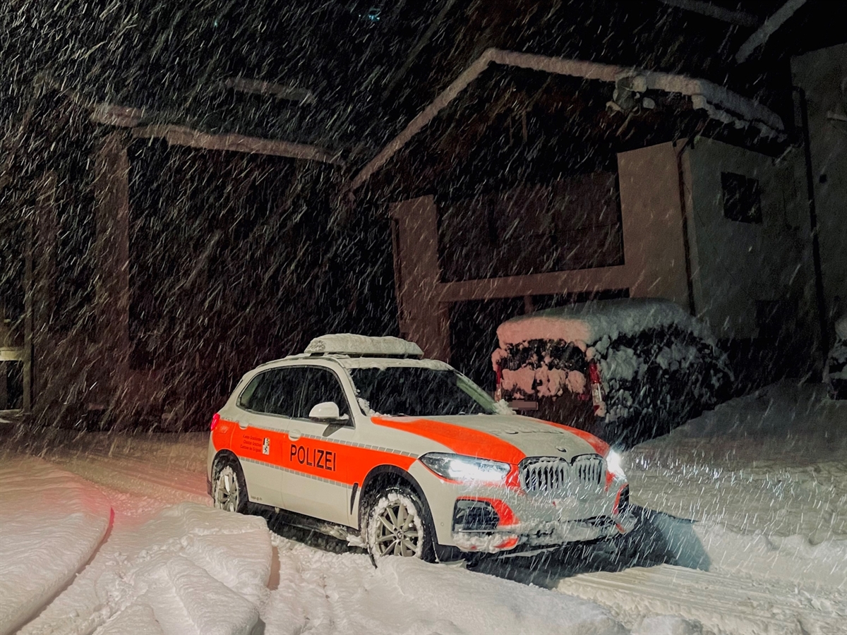 Ein Polizeiauto steht in einem verschneiten Dorf. Schneefall. 
