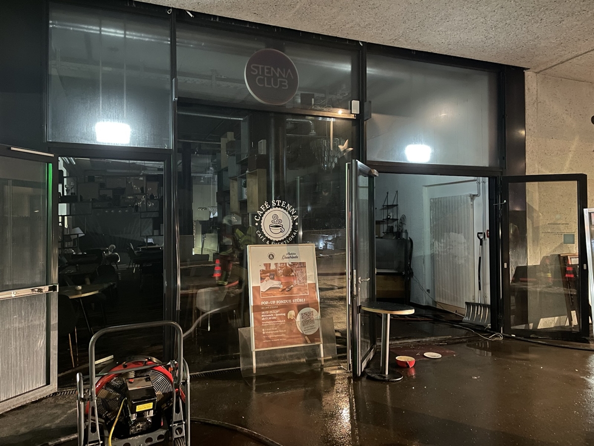 Der Eingang zum Café Stenna. Vor den Türen steht ein Ventilator der Feuerwehr Flims. Der Boden ist mit Wasser durchtränkt.