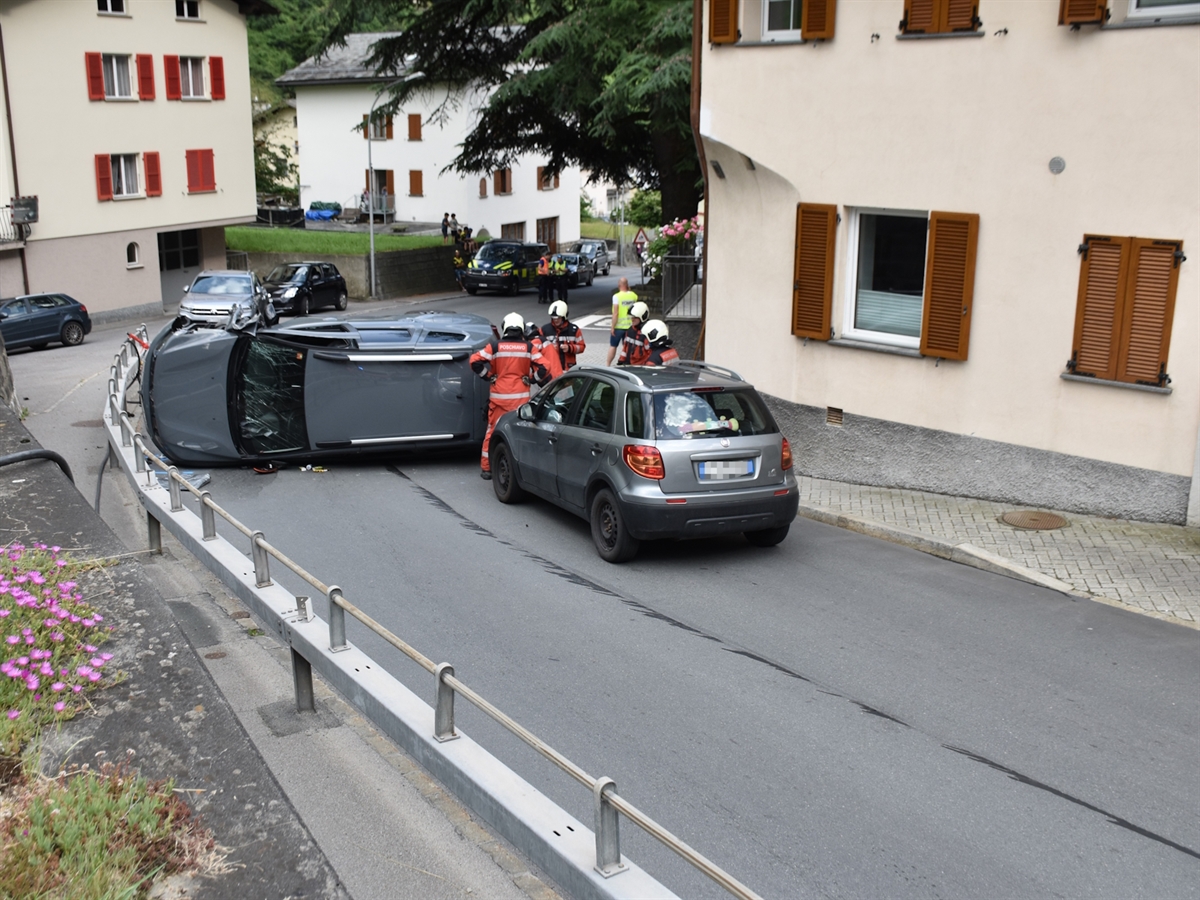 Das mitten auf der Strasse liegende Auto. Daneben sowie im Hintergrund Einsatzkräfte und weitere Personen. Die Strasse ist abgegrenzt durch Gebäude.