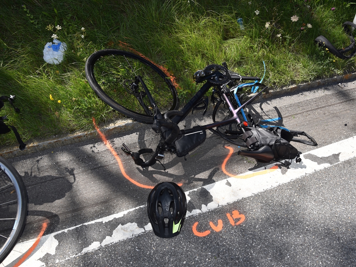 Ein am Boden liegendes Rennrad mit komplett beschädigtem Heck. Daneben ein Helm.