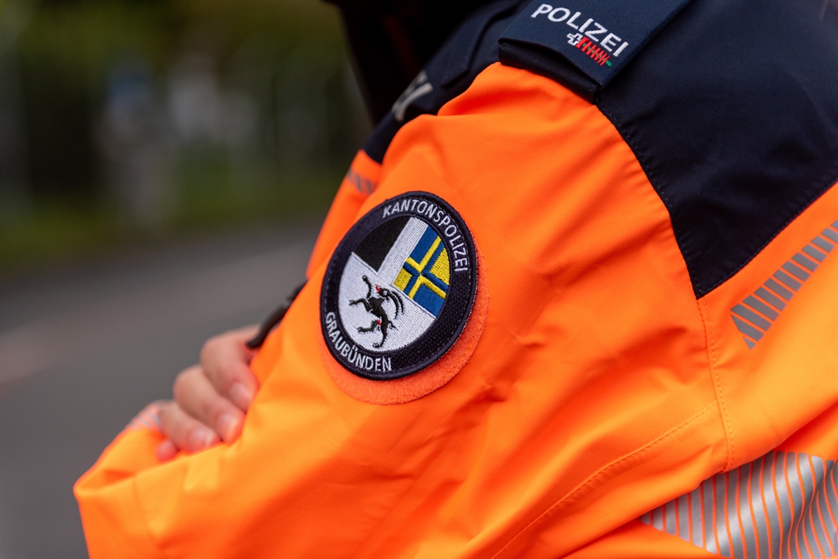 Polizist mit oranger Jacke mit Logo auf Ärmel