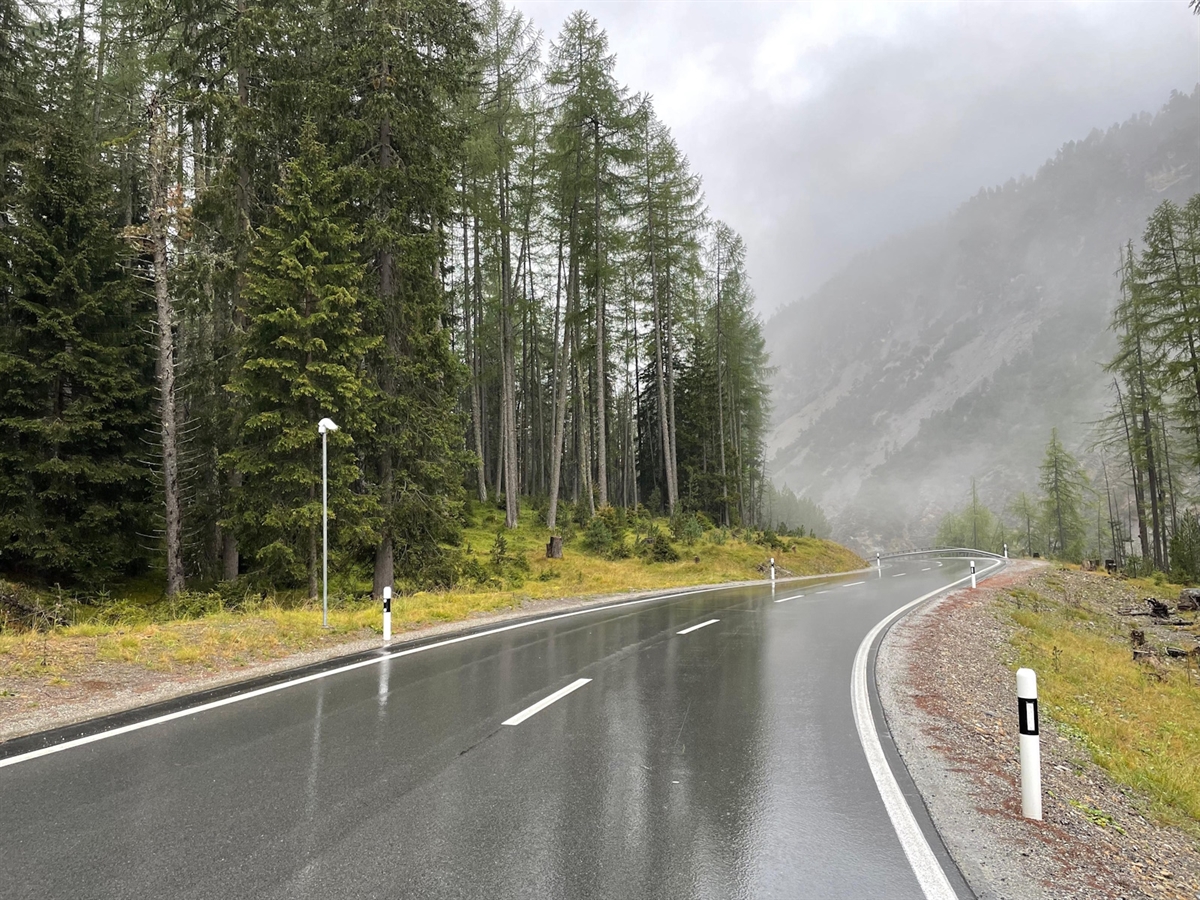 Die Rechtskurve welche in eine Linkskurve übergeht. Die Strasse ist umsäumt von Wald.