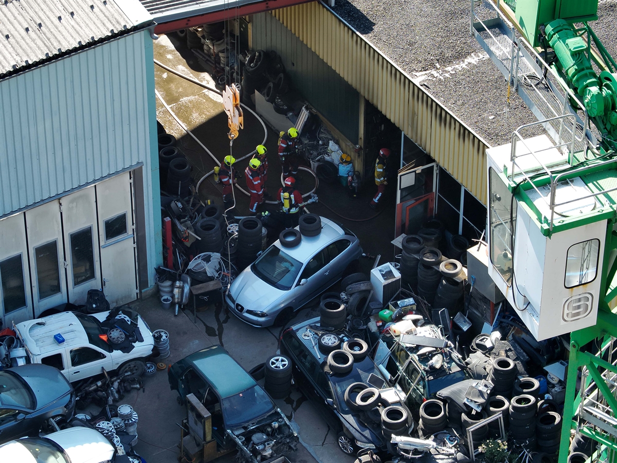 Luftaufnahme Hallen mit abgestellten Fahrzeugen und Feuerwehr