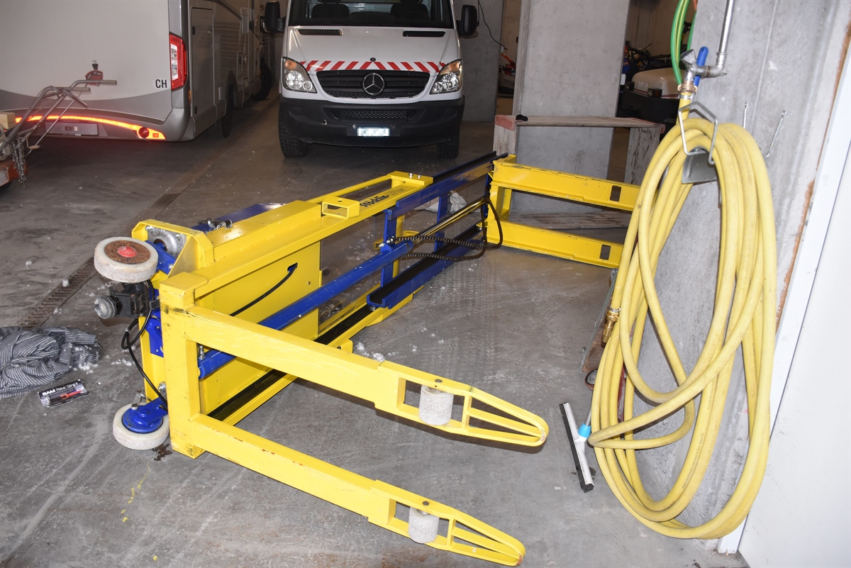 Auf dem Boden liegt der umgekippte gelbblaue Hochhubwagen.