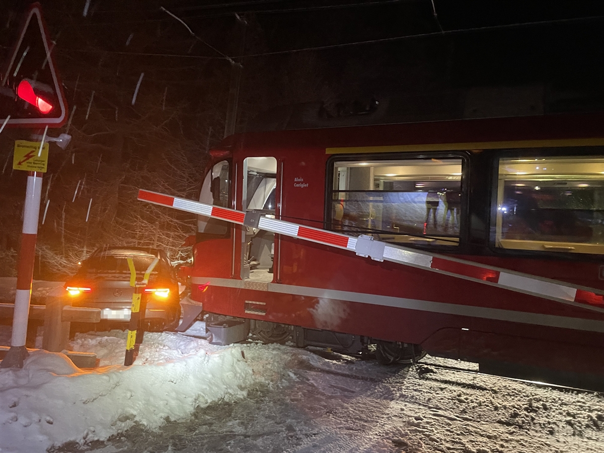 Nachtaufnahme mit dem Unfallauto vor dem Zug. Die Barriere ist leicht geöffnet.