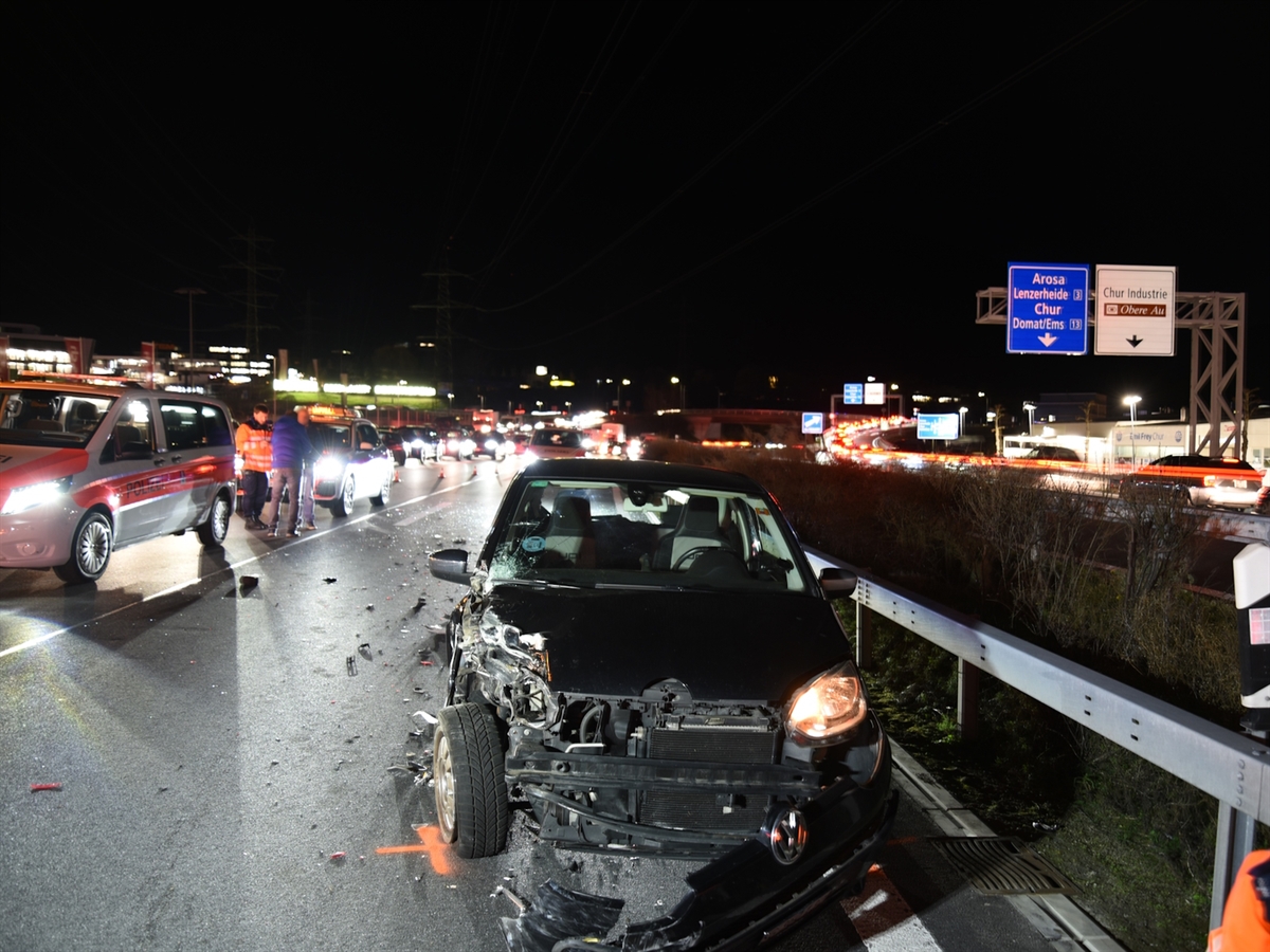 Das Auto des Verursachers steht auf der Überholspur, rechts der Mittelleitplanke vorne gesehen. Die gesamte Front, insbesondere der linke Teil der Front, ist total beschädigt. Links auf der Normalspur steht ein Polizeifahrzeug, hinter welchem ein Polizist mit zwei Personen diskutiert.