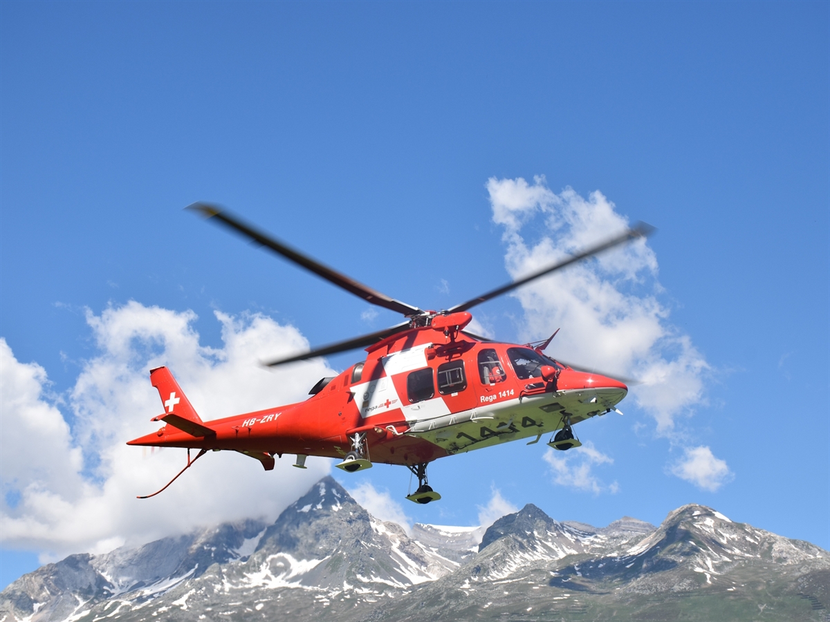 Ein Helikopter der Rega in malerischem Berggebiet unterwegs