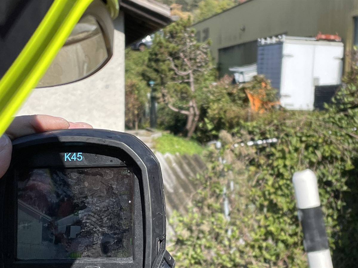 Ein Feuerwehrmann misst mit einer Wärmebildkamera die Temperatur des Brandobjekts im Hintergrund.