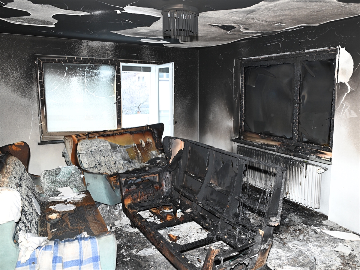 Blick in das Wohnzimmer mit verbrannten Möbeln und verrussten Wohnungswänden.