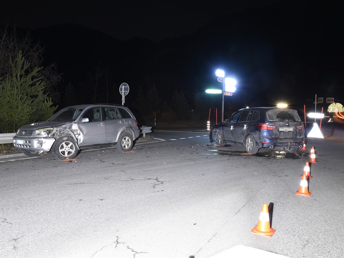 Nachtaufnahme der Querverbindung mit Leitkegel, welche die Unfallfahrzeuge sichern. Im Hintergrund das Tunnelportal vom Tunnel Sils. Links im Bild der silber-graue Personenwagen des Entgegenkommenden. Dieser ist vorne links total beschädigt. Rechts im Bild steht das Auto der Frau mit ebenfalls einer Beschädigung an der linken Fahrzeugfront.