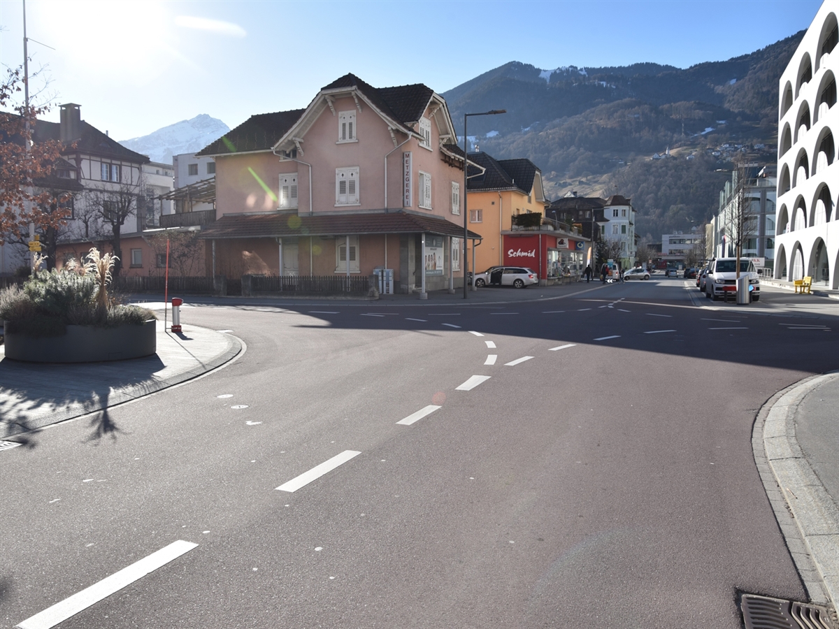 Die Verzweigung Bahnhofstrasse/Schulstrasse in Richtung Bahnhof Landquart gesehen. Durch Leitlinien werden die Fahrspuren getrennt und der Verkehrsteilnehmer auf den sogenannten Rechtsvortritt aufmerksam gemacht. Die Verzweigung wird durch Gebäude und Trottoire begrenzt