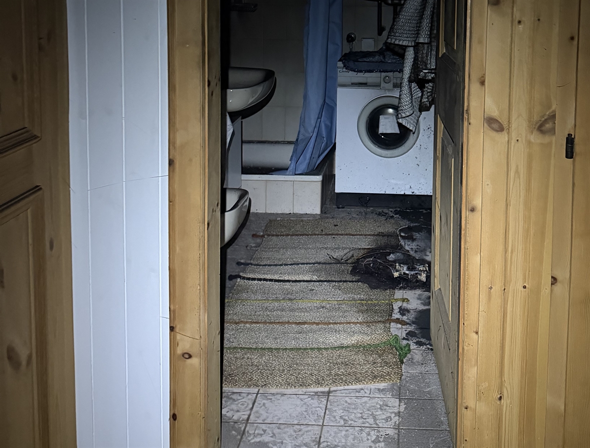 Blick ins Bad mit Waschmaschine und angebranntem Teppich