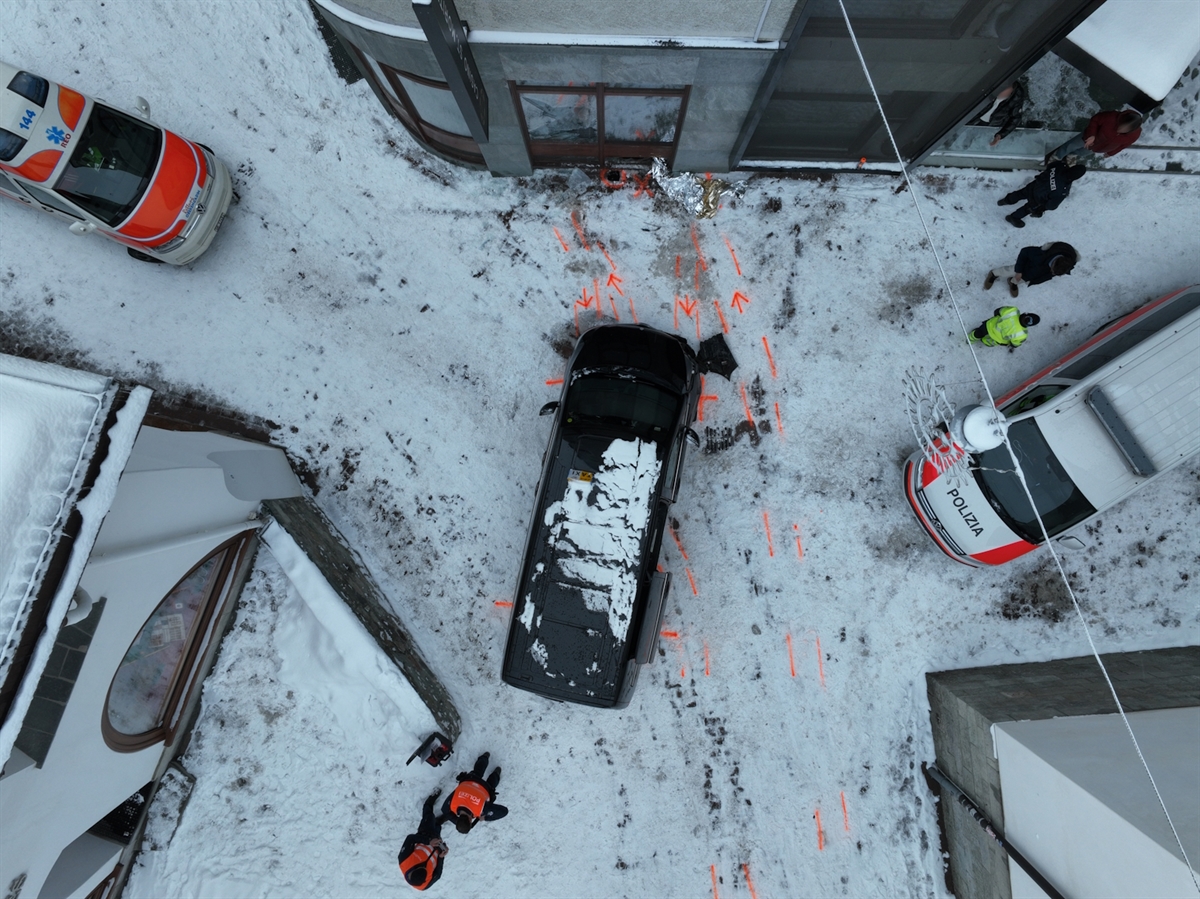 Luftaufnahme auf die Unfallstelle. Mittig das Unfallauto, links und rechts davon je ein Einsatzfahrzeug. Auf der winterlichen Strasse eingezeichnete Spuren der Unfalldynamik.