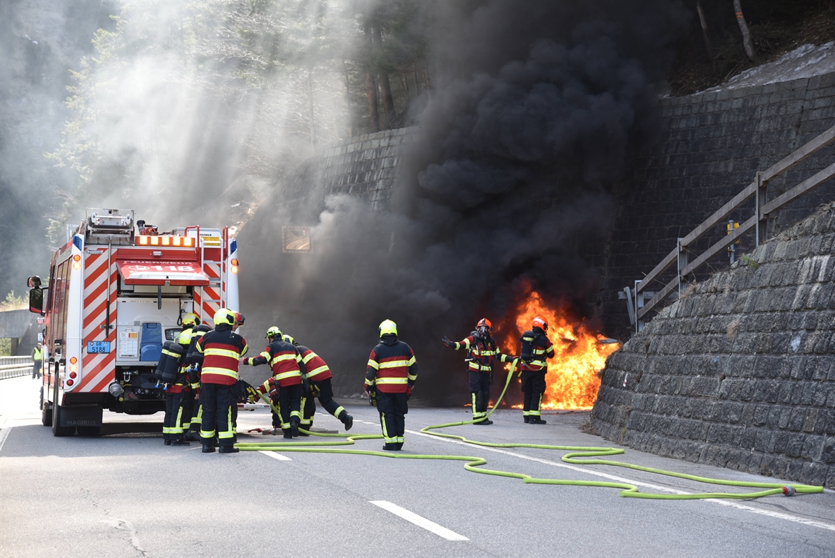 Feuerwehrauto und Feuerwehrleute, Auto mit Flammen und schwarzem Rauch