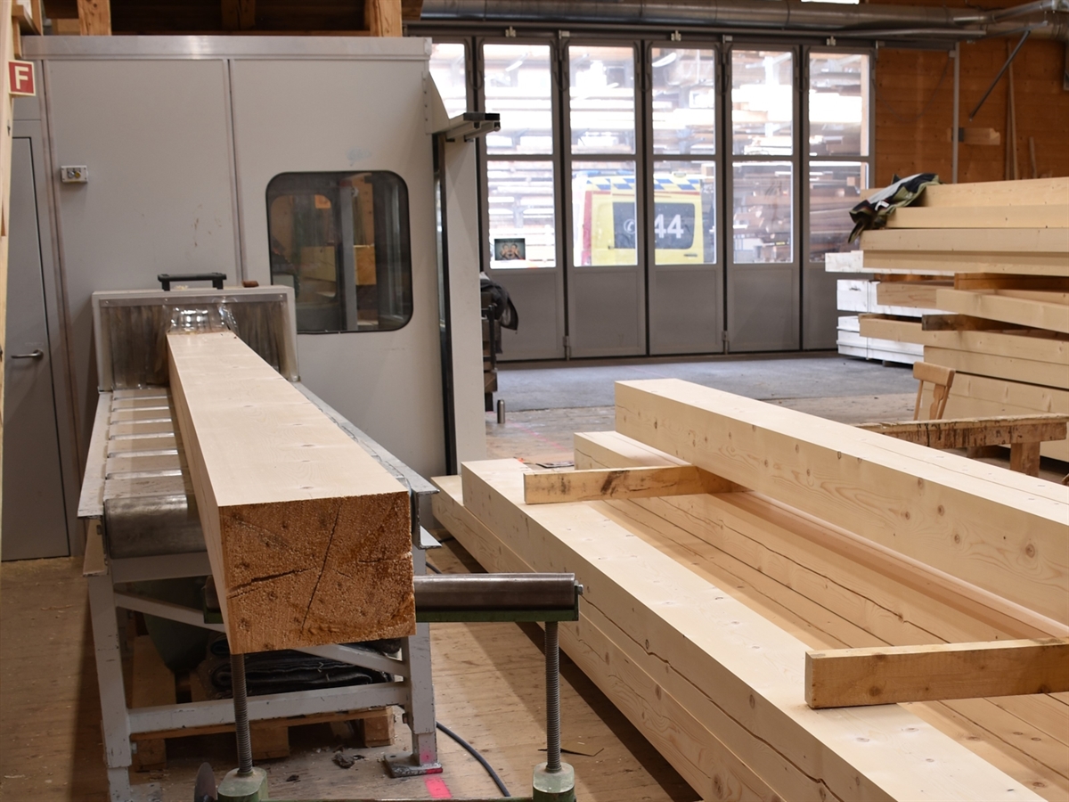 Aufnahme im Gebäudeinnern mit aufgestapelten Holzbalken und der Hobelmaschine. Im Aussenbereich ein Rettungswagen.