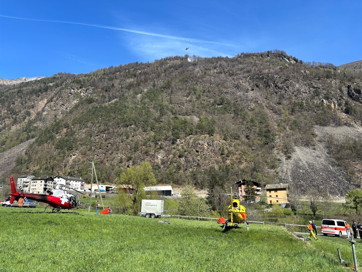 Übersichtsaufnahme des Hanges der gebrannt hat. Zwei zivile Helikopter am Boden und ein Superpuma in der Luft
