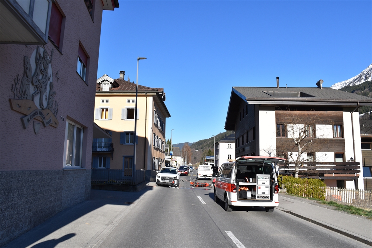 Im Vordergrund ein Polizeiauto. Dahinter das Auto aus der Gegenrichtung sowie das am Boden liegende Motorrad. Im Hintergrund Berge und wolkenloser Himmel.
