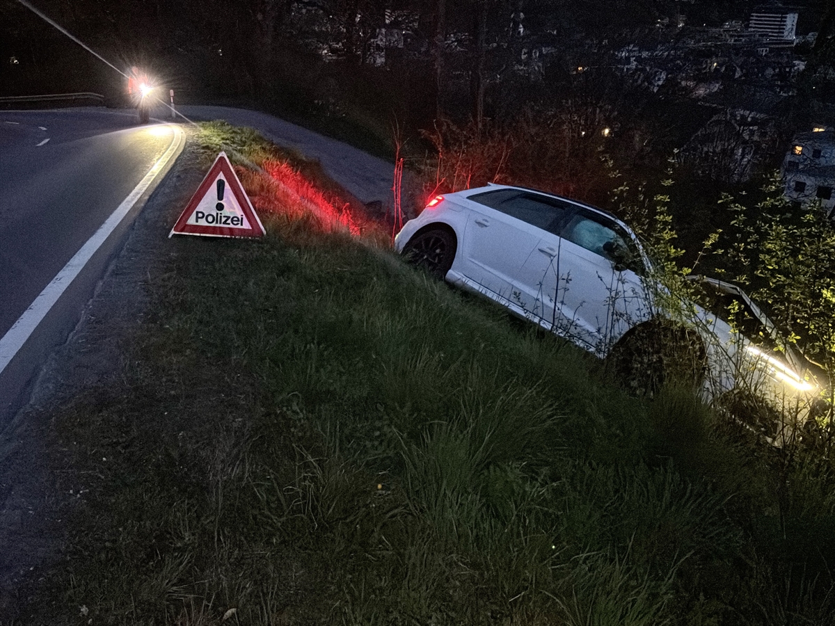 Das Unfallauto in der Böschung. Auf der Strasse ein Faltsignal mit der Aufschrift 