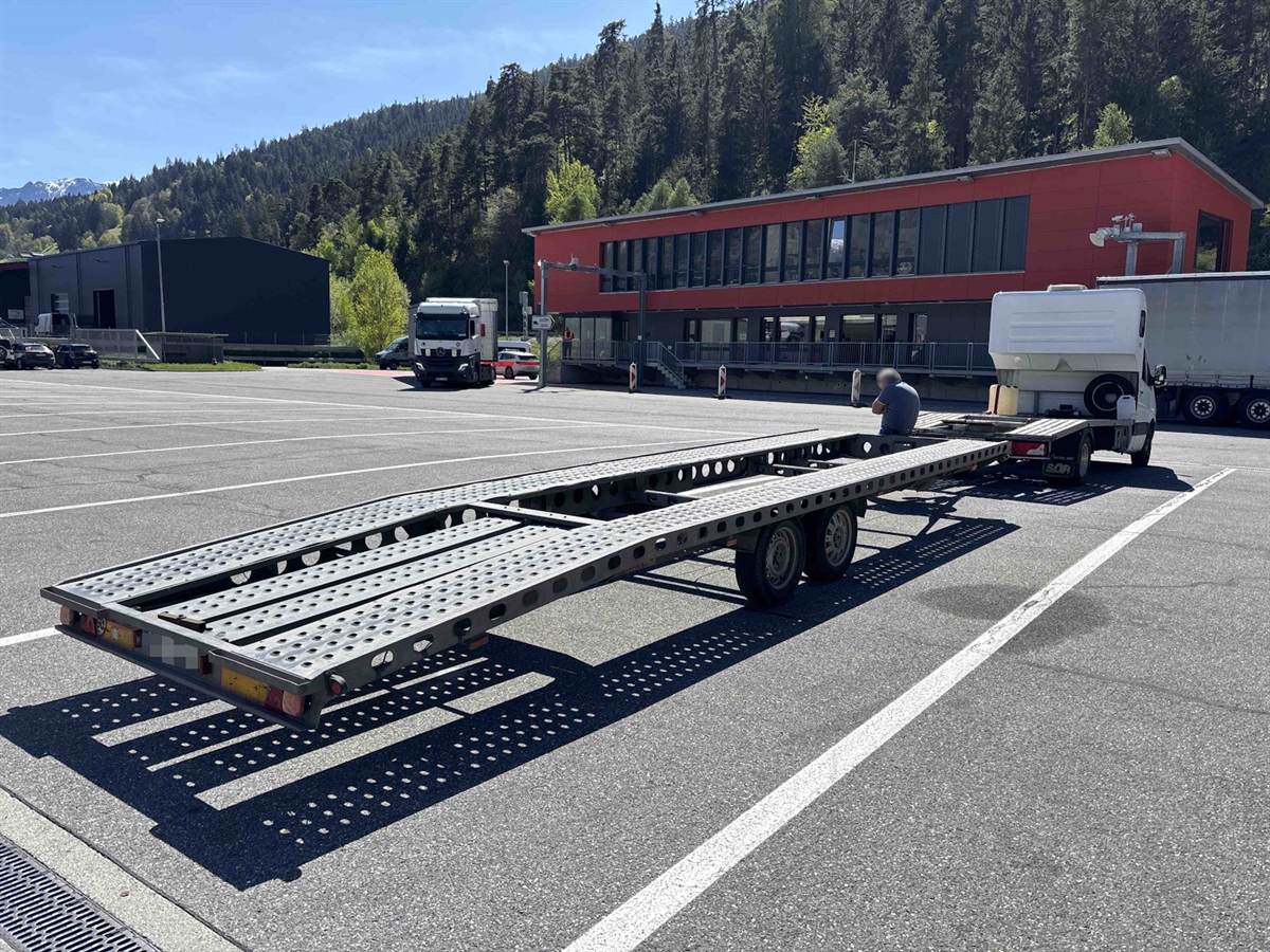 Der leichte Autotransporter steht auf dem Kontrollplatz des Schwerverkehrskontrollzentrums in Unterrealta. Im Hinterung das Gebäude sowie die Wägeplatten mit Profileranlage.