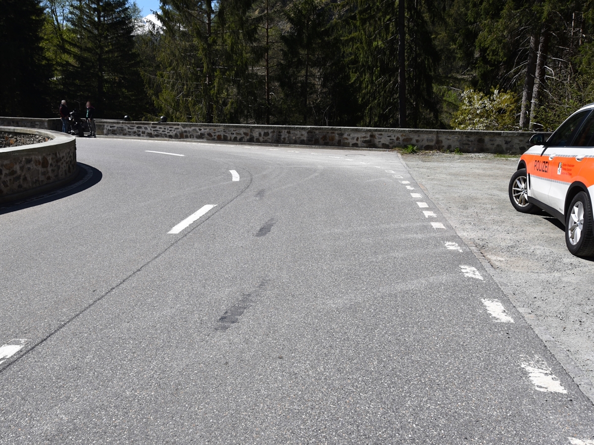 Der Strassenverlauf der Via Mala. Die Linkskurve führt geradewegs auf eine Brücke über den Hinterrhein. Auf dem Platz rechts neben der Strasse steht ein Polizeifahrzeug.