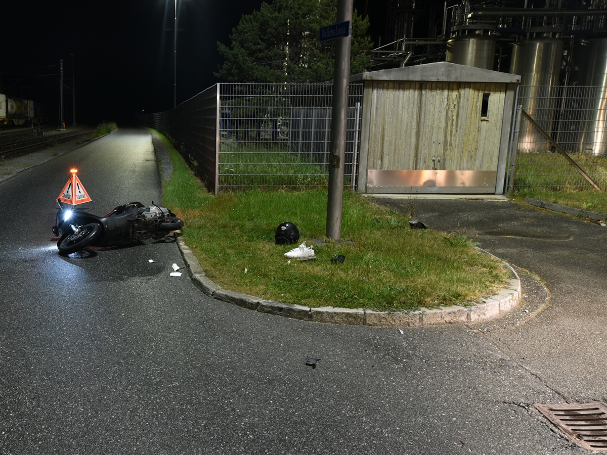 Eine mit Randsteinen abgegrenzte Verkehrsinsel. Daneben auf der Strasse das liegende Unfallmotorrad sowie ein Faltsignal.