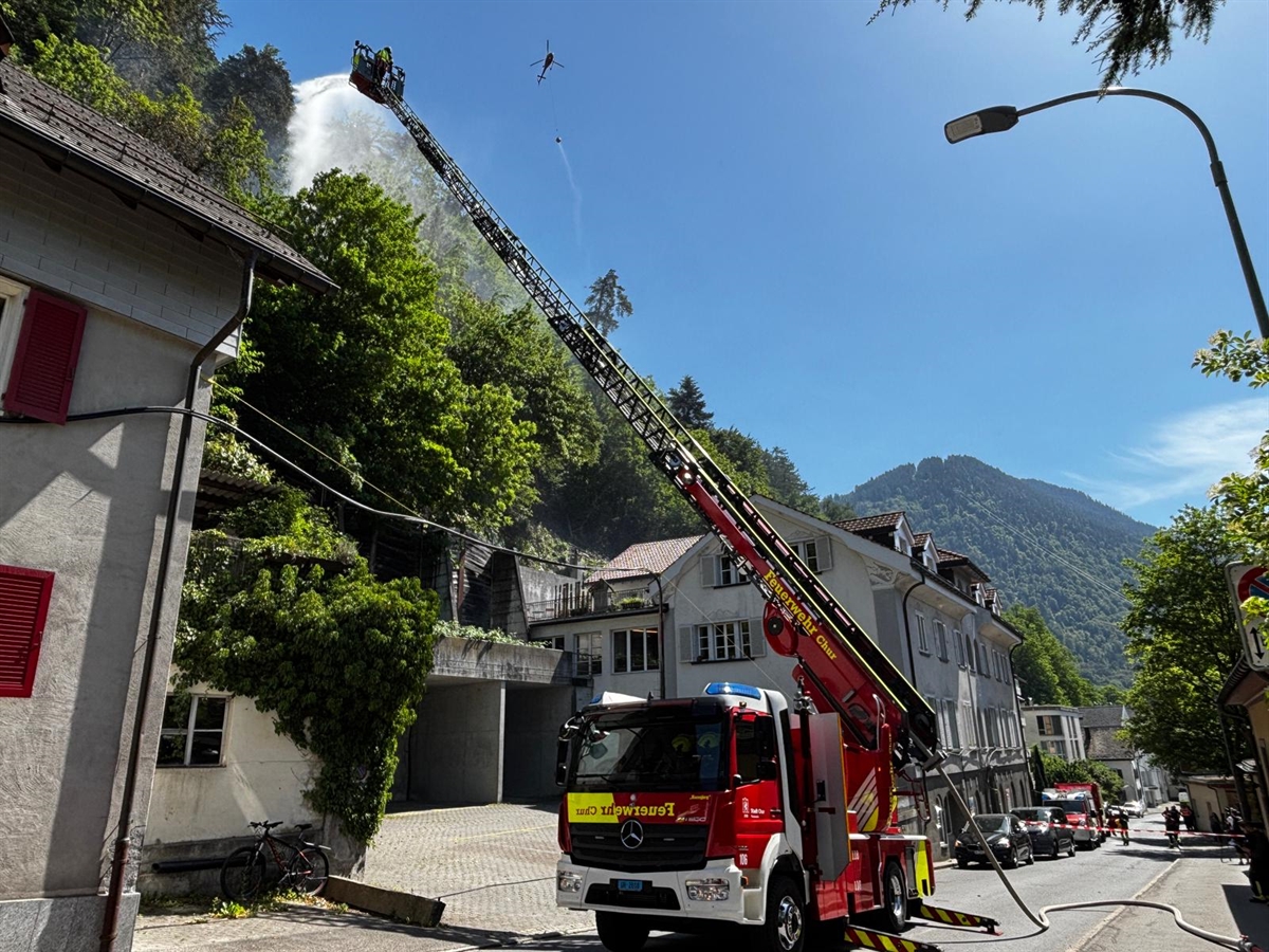 Die Feuerwehr Chur mit Hebebühne, im Hintergrund Rauch mit den Löschhelikoptern.