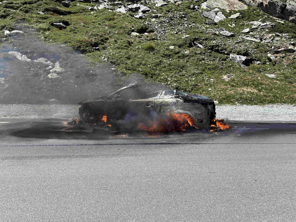 Das noch brennende Auto steht am Strassenrand. Es steigt rauch auf.