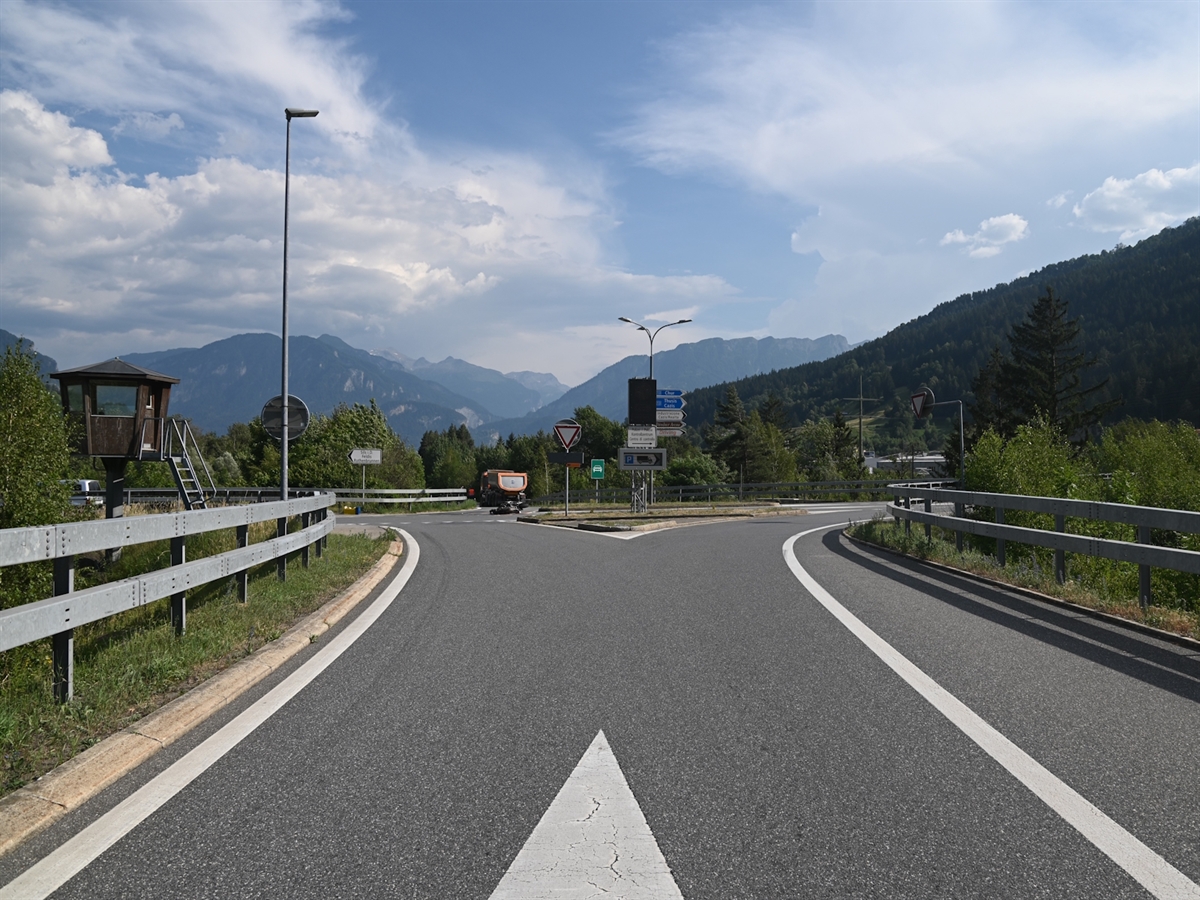 Sicht von der Autostrasse kommend auf die Querverbindung mit dem Verkehrsteiler sowie den Signalen mitten im Bild. Auf der Fahrbahn der Querverbindung liegt das Motorrad. Weiter hinten, bereits wieder auf der Einfahrt zur A13, steht das Sattelmotorfahrzeug.