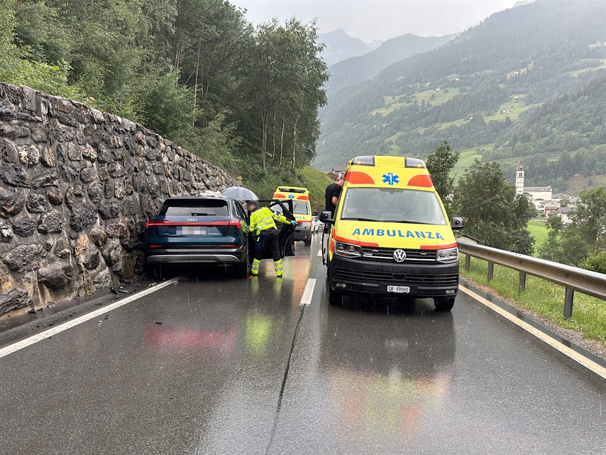 Auf der Berninastrasse steht das Unfallfahrzeug neben der Stützmauer. Rettungssanitäter betreuen die Fahrzeuginsassen. Neben dem Auto steht eine Ambulanz. Hinter dem Unfallauto steht eine weitere Ambulanz.