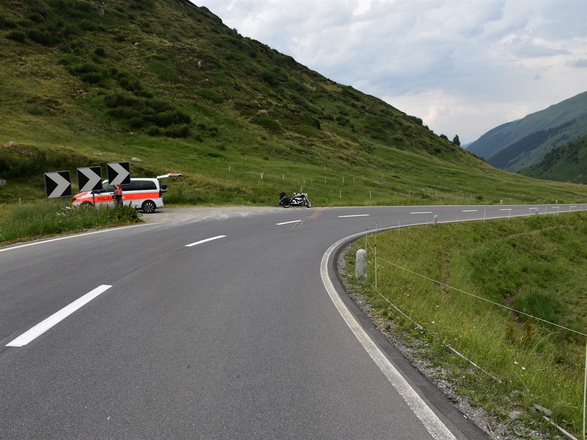 Die Rechtskurve am Oberalppass. Am linken Strassenrand stehen ein Polizeiauto sowie das verunfallte Motorrad. Ein Polizist steht neben dem Patrouillenwagen.