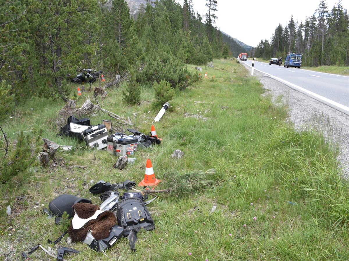 Motorradteile liegen im Wiesland verteilt neben der Ofenbergstrasse. Auf der Strasse stehen mehrere Fahrzeuge.