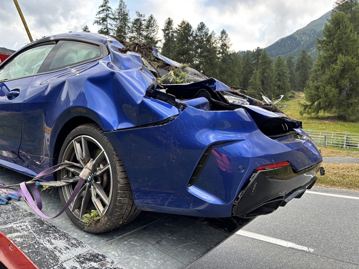 Teilaufnahme des total beschädigten und im Heckbereich zerquetschten Autos.