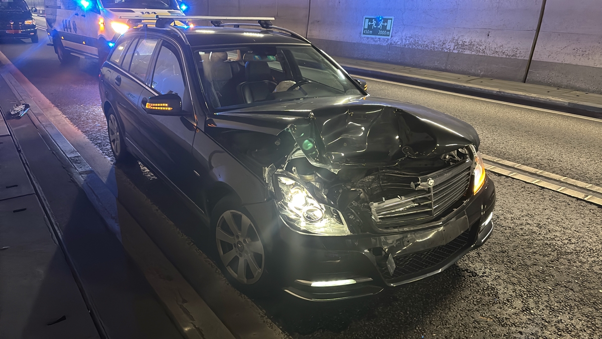 Im Vordergrund ist der massiv beschädigte dunkle Personenwagen zu erkennen, welcher dem anderen Fahrzeug auffuhr. Im hinteren Teil ist ein Rettungswagen zu erkennen.