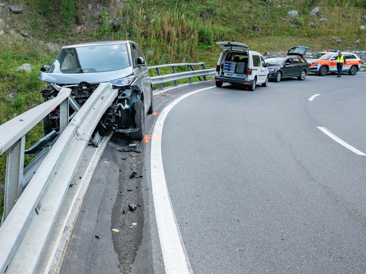 Der total beschädigte Personenwagen auf der Brücke, verkeilt mit der Leitplanke. Auf der Fahrbahn liegen Trümmerteile herum und orange Markierungen der Spurensicherung sind sichtbar. Im Hintergrund stehen weitere Fahrzeuge sowie ein Polizeifahrzeug.